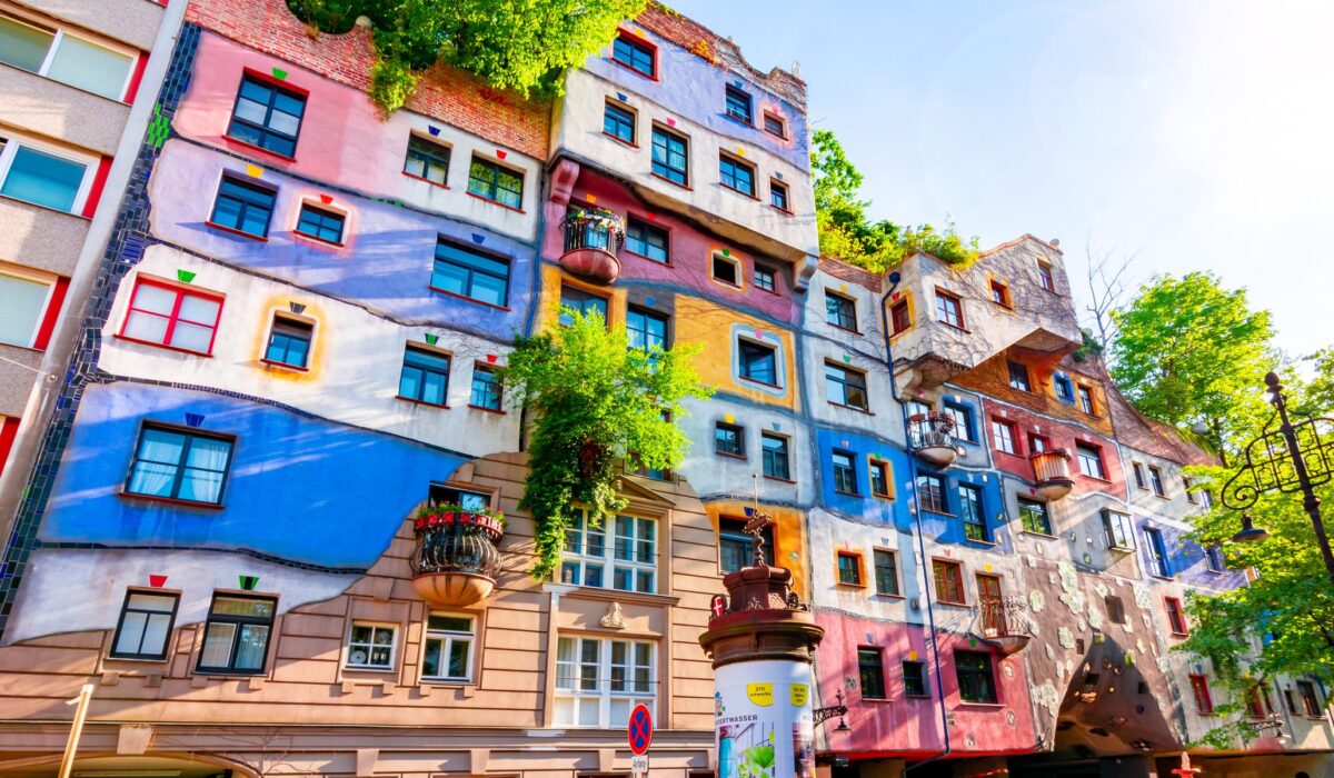 Fachada colorida de La Casa Hundertwasser en Viena, con formas onduladas y vegetación.