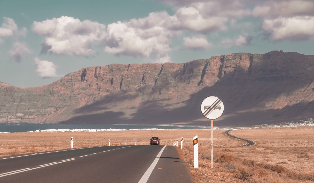 Impresionante paisaje de Lanzarote con montañas volcánicas, carretera y playa con olas