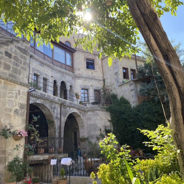 Patio de un hotel en Capadocia, adornado con plantas y decoraciones típicas de la región, con un ambiente acogedor y vistas de las chimeneas de hadas