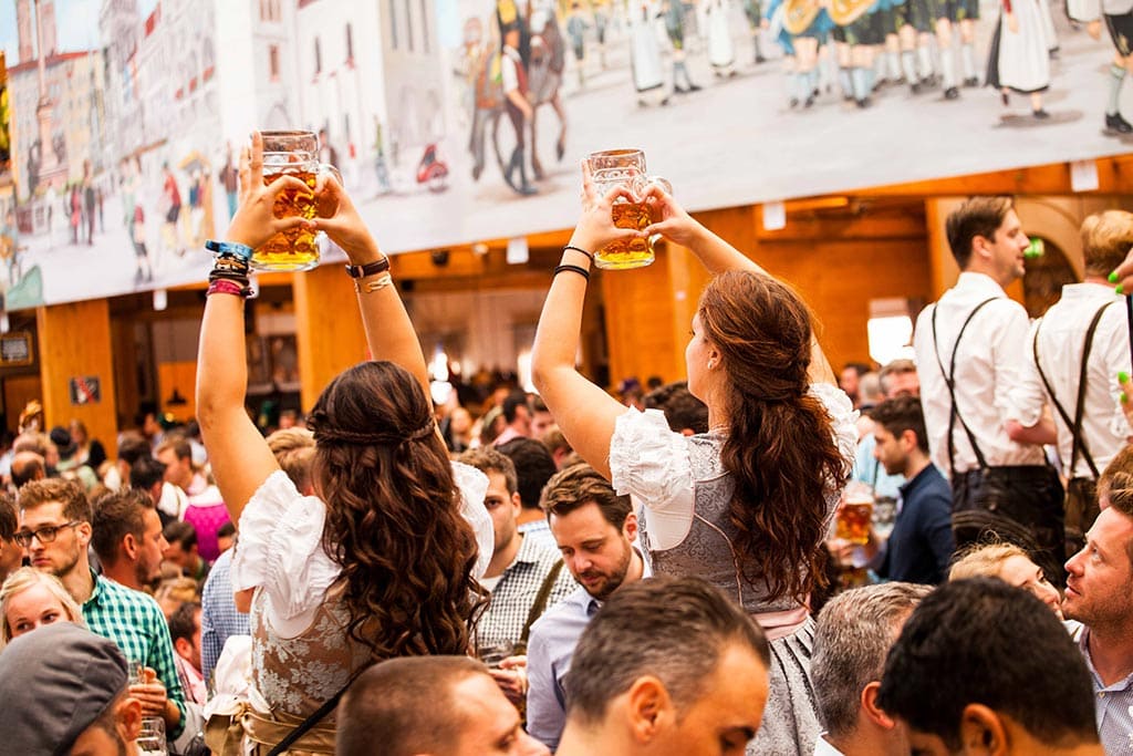 Celebración de Oktoberfest con personas disfrutando de cerveza y música en Múnich, Alemania