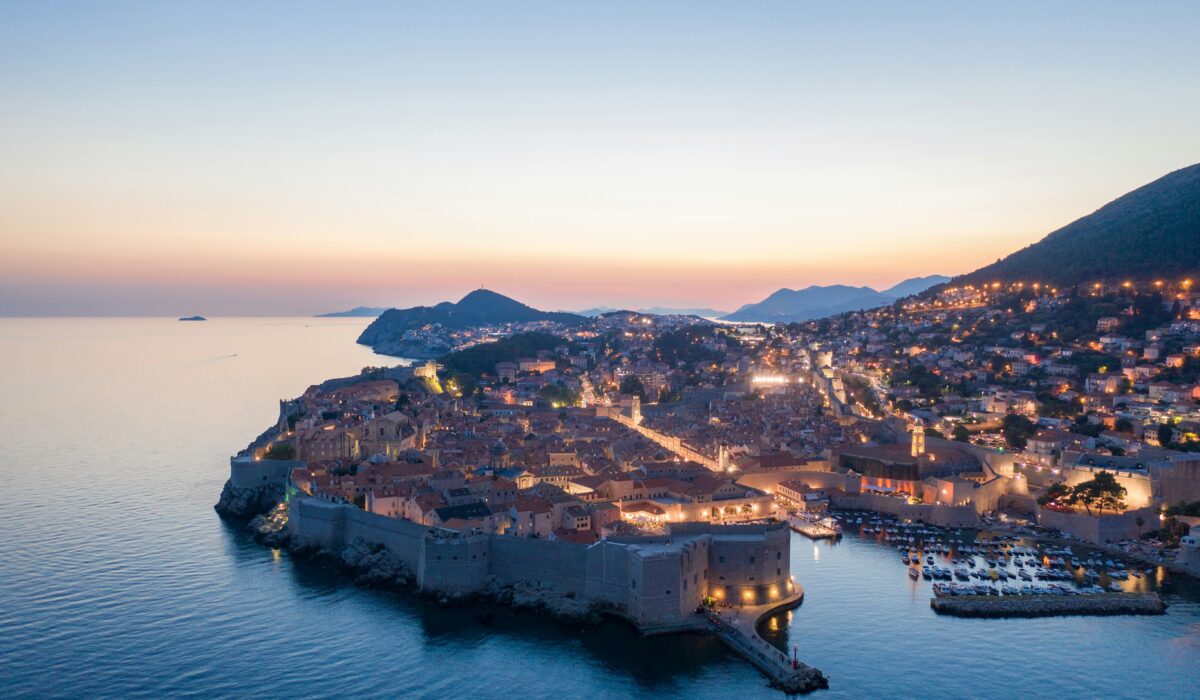 Panorámica nocturna de Dubrovnik iluminada, con sus murallas y el mar Adriático