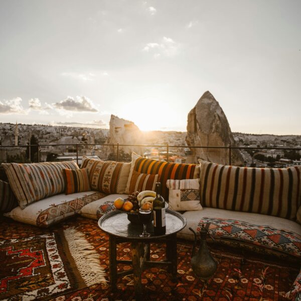 Terraza con típicos sofás turcos, decorada con cojines coloridos, mientras se observa el atardecer sobre las chimeneas de hadas en Capadocia.