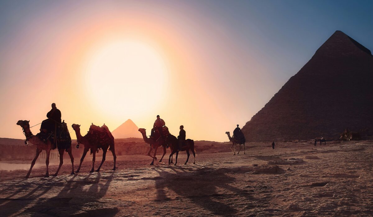 Pirámides de Egipto al atardecer con camellos cruzando el desierto