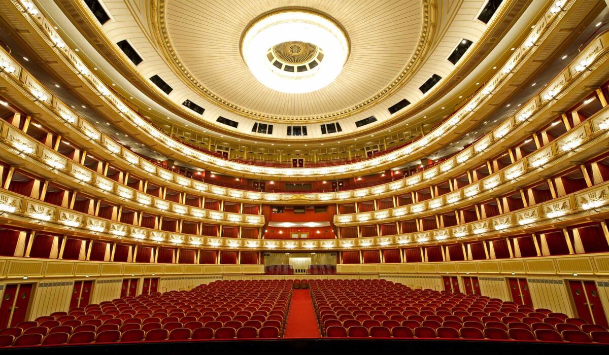 Sala majestuosa de la Ópera Estatal de Viena, con detalles ornamentados y butacas rojas.