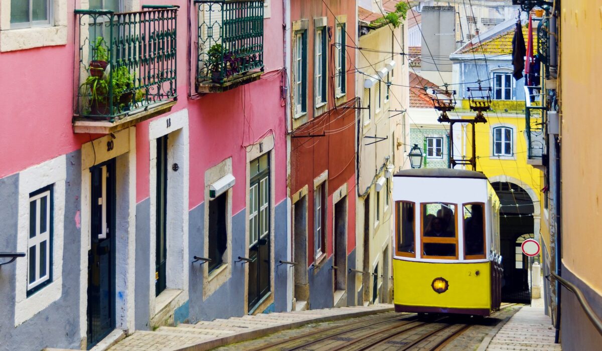 Tranvía amarillo atravesando una calle estrecha en Alfama, Lisboa