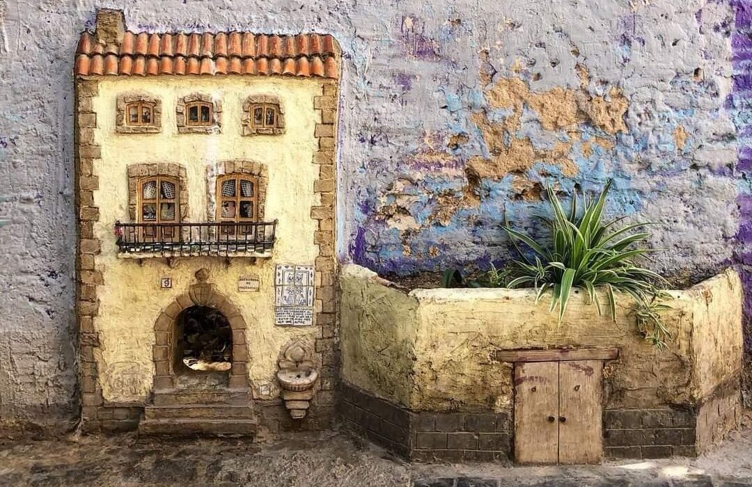 Pequeño agujero en el muro de la Casa de los Gatos en Valencia, adornado con una pintura encantadora.