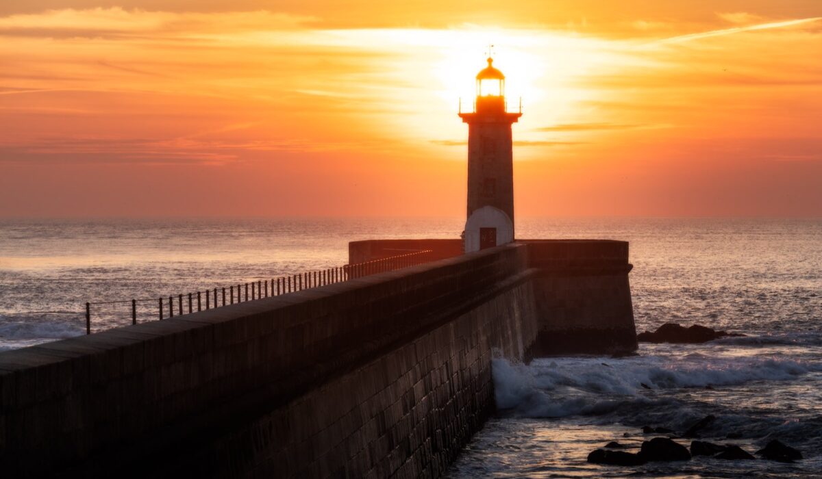 Faro de Felgueiras iluminado por el atardecer, junto al mar en Oporto.