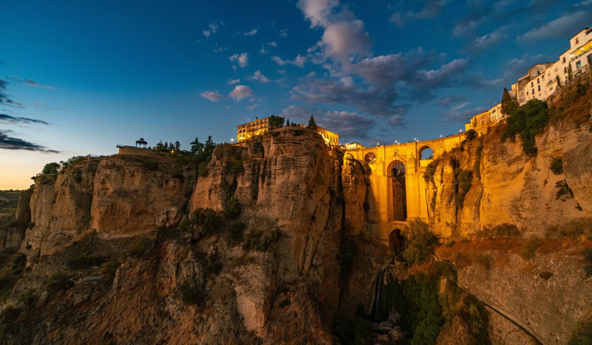 Vista del Puente Nuevo de Ronda, iluminado por el sol, con el pueblo andaluz de fondo.