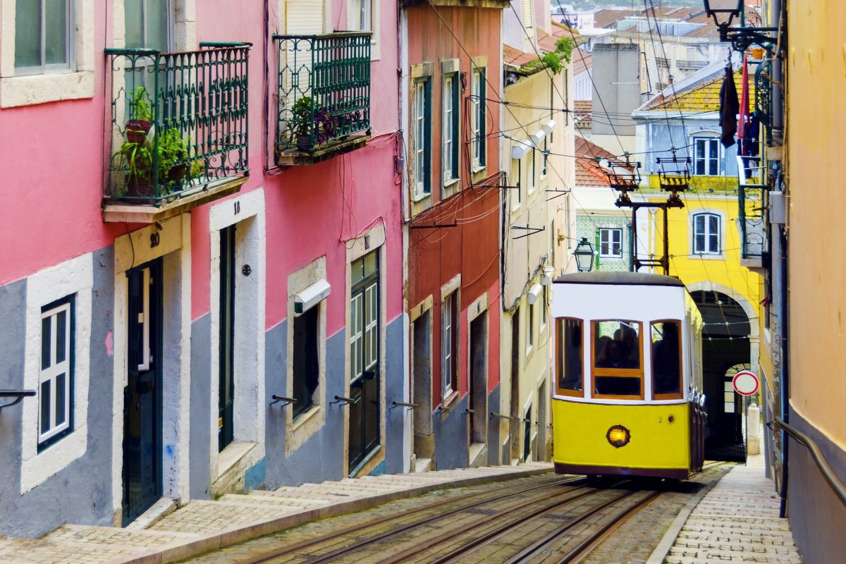 Tranvía amarillo atravesando una calle estrecha en Alfama, Lisboa