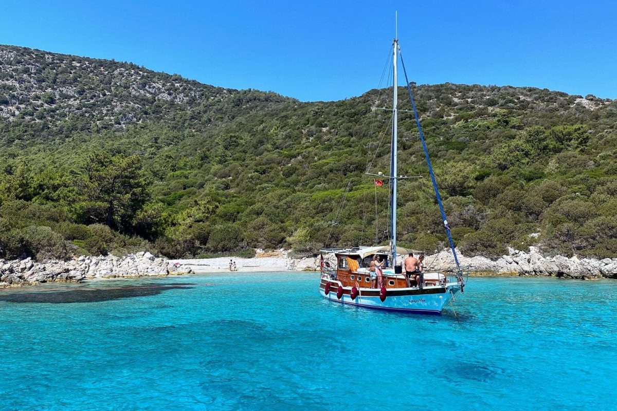 Velero flotando en aguas cristalinas del mar de Bodrum cerca de una isla remota